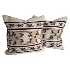 two decorative pillows made out of wool with geometric designs on them, one is white and the other is brown