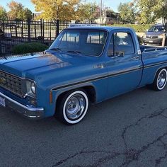 an old blue pickup truck parked in a parking lot