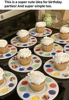 cupcakes with white frosting and sprinkles on plates in front of an oven