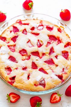 a pie with strawberries on the side sitting on top of a white table next to sliced strawberries