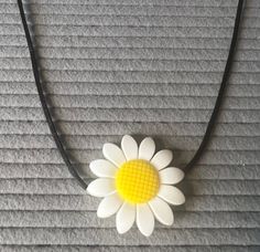 a white and yellow flower sitting on top of a black cord