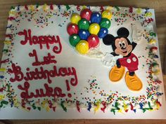 a birthday cake decorated with mickey mouse and balloons