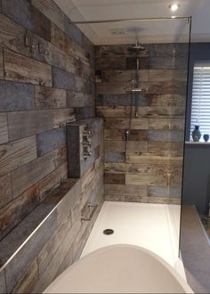 a bathroom with wooden walls and a white bathtub next to a walk in shower