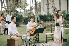 a man and woman playing music in front of a group of people on lawn chairs