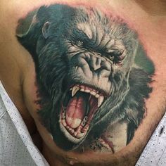 a man's chest with an angry gorilla tattoo on the chest and his mouth open