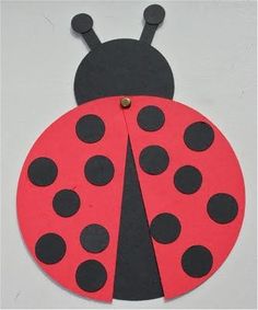 a paper ladybug with black dots on it's back and red body