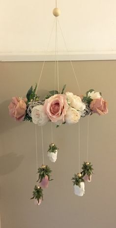 a mobile with flowers hanging from it's sides on a wall in a room