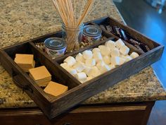 a wooden tray filled with marshmallows on top of a counter