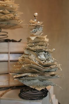 a small christmas tree made out of old newspaper strips and other papers on a table