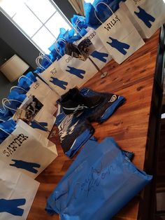 blue and white paper bags are lined up on a table with shoes, socks, and other items