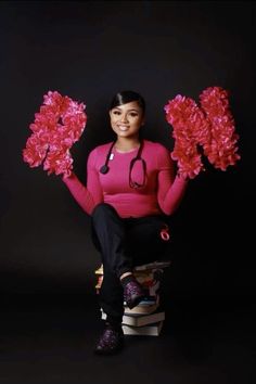 a woman sitting on top of a stack of books holding red pom poms