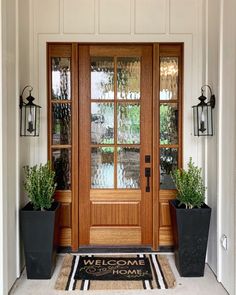 a front door with two planters and a welcome mat