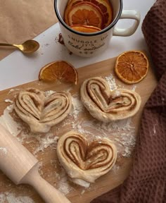 some oranges and cinnamon rolls on a cutting board next to a cup of coffee