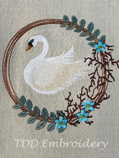 a white swan with blue flowers on it's head is surrounded by leaves and branches