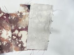 two pieces of fabric with white and brown designs on them, one is torn off