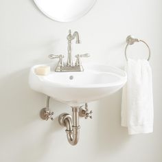 a white bathroom sink sitting under a mirror next to a wall mounted faucet