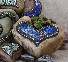 some rocks with designs on them and a plant growing out of the heart shaped rock