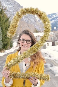 a woman is holding up a heart made out of tinsel and gold garlands