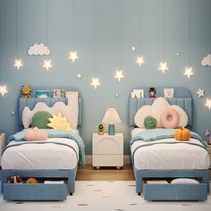 two children's beds in a blue bedroom with stars on the ceiling and lights above them