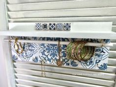 several bracelets are hanging on the window sill in front of an ornate blue and white wall