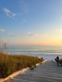 a person sitting on a wooden walkway next to the ocean