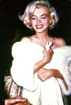 marilyn monroe is smiling while holding her coat