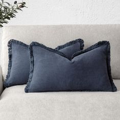 two blue pillows sitting on top of a couch