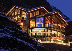 a large house is lit up at night with lights on the windows and balconys