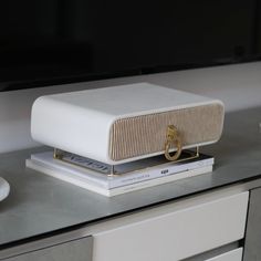 a white speaker sitting on top of a stack of books