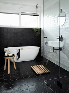 a bathroom with black and white tile on the walls, floor, and bathtub