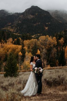 a bride and groom standing in front of a mountain