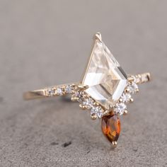 a ring with an orange and white diamond on it's side, set in yellow gold