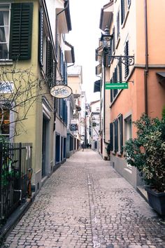 an alley way with several buildings on both sides and a street sign hanging from the side