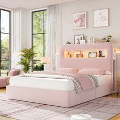 a pink bed in a white room with lots of windows