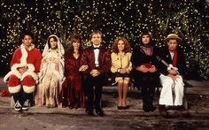 a group of people dressed in costumes sitting on a bench next to a christmas tree