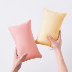 two pillows being held up in the air