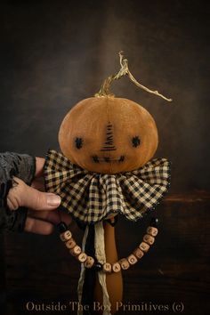 a hand holding a pumpkin with a black and white checkered bow