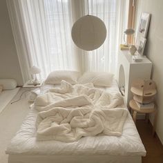 an unmade bed with white sheets and blankets on it in a bedroom next to a window