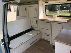 the inside of a camper van with cabinets and drawers on each side, looking into the kitchen