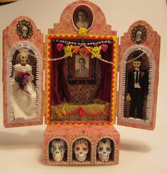 an elaborately decorated dollhouse with three dolls in it's display case, including a bride and groom