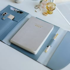 a blue folder with a notepad and pen sitting on top of it next to other items