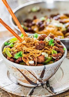 a bowl filled with noodles and meat on top of a plate next to another bowl