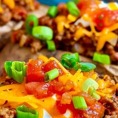 some taco shells are topped with cheese and other toppings on a wooden board