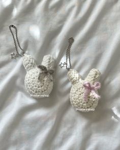 two crocheted keychains are laying on a white sheet, one is shaped like a bunny and the other has a pink bow