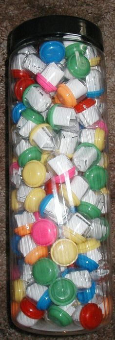 a jar filled with lots of colorful plastic spoons on top of a carpeted floor