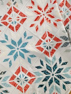 a close up of a quilt with red, white and blue snowflakes on it