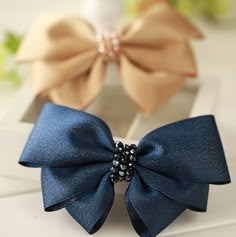 two bows with pearls on them sitting next to each other in front of a vase