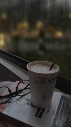 a cup of coffee sitting on top of a stack of books next to a window