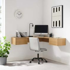 a desk with a computer on it next to a potted plant and a clock