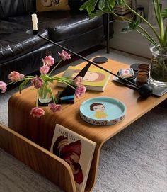 a coffee table with flowers in a vase on top and magazines under the table next to it